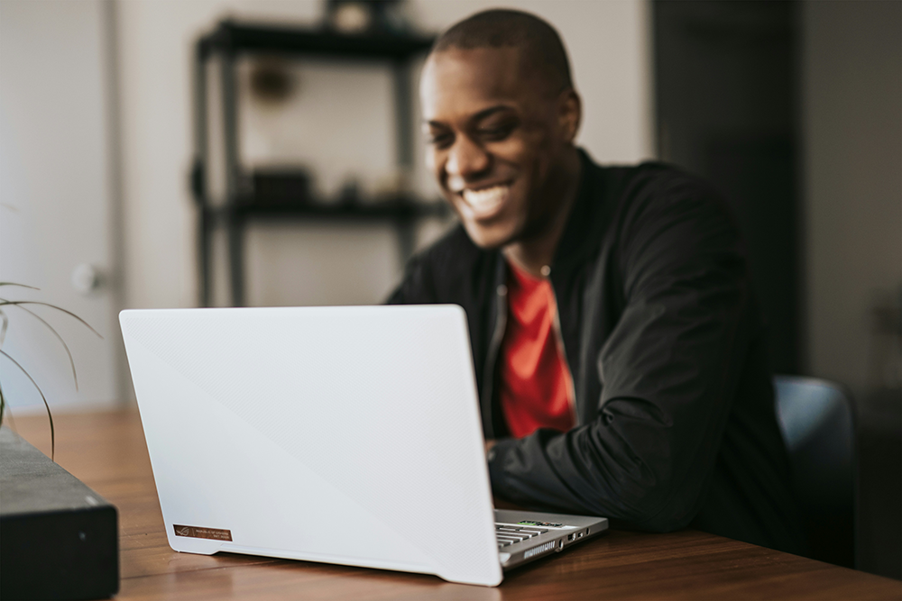 Smiling man on computer at dining room table