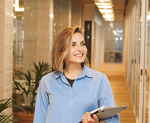 Woman smiling in an office holding a laptop