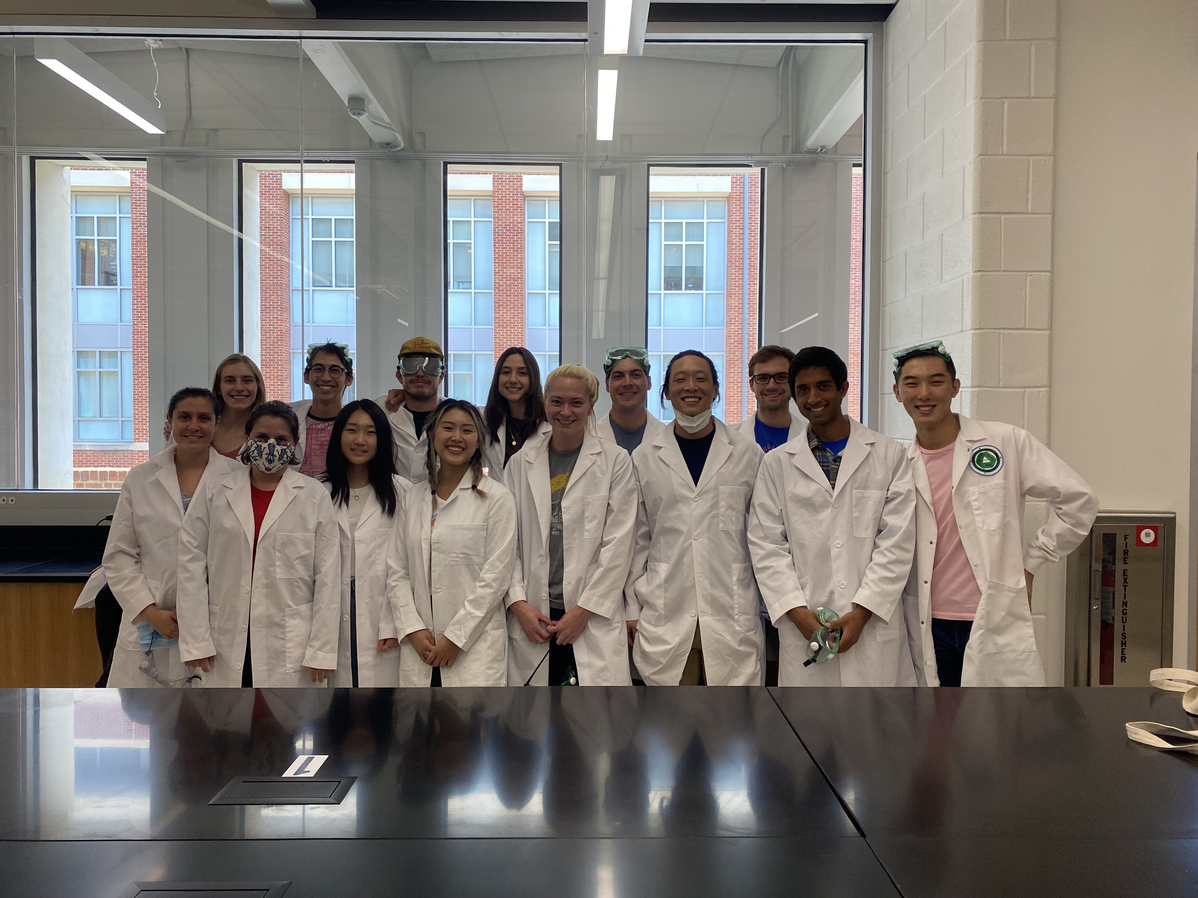 Group of post bacc pre-med students in white coats smiling at camera in medical classroom