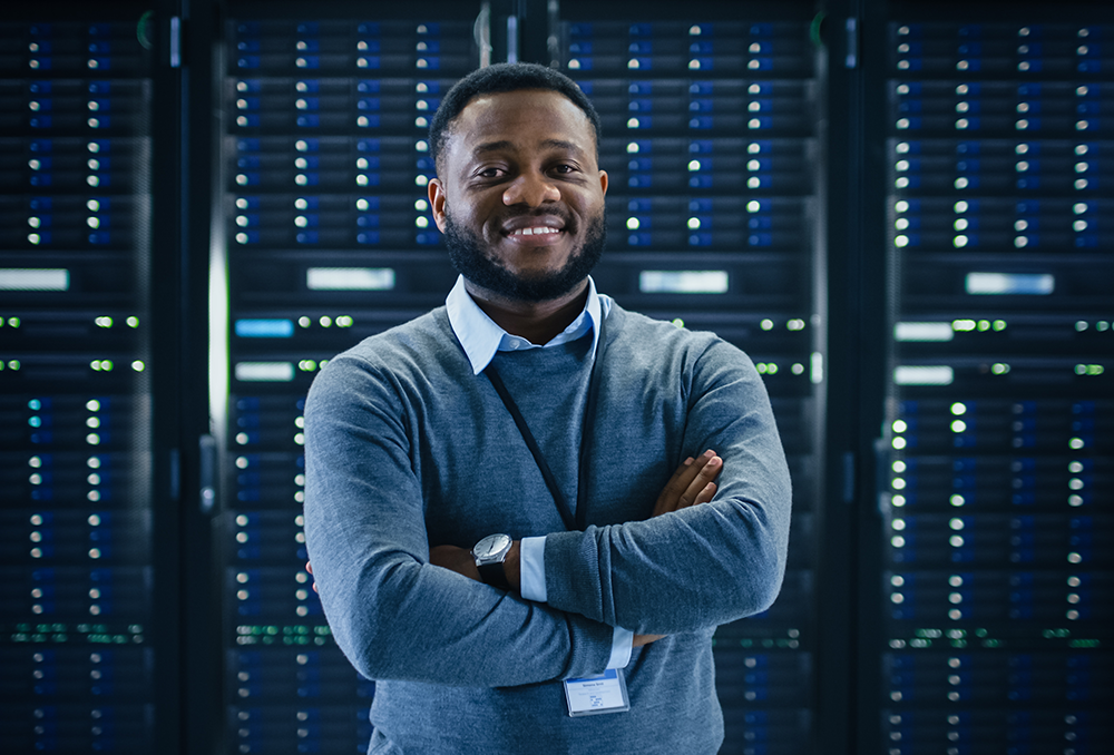 African american male computer technician smiling with arms crossed infront of computer hardware