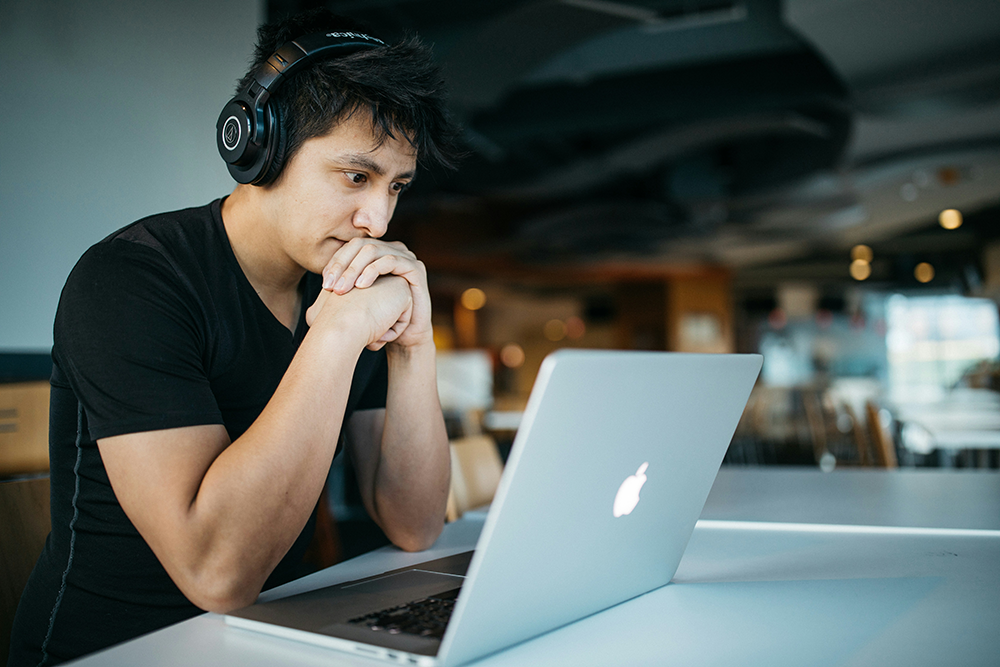 Man with headphones intently learning on computer