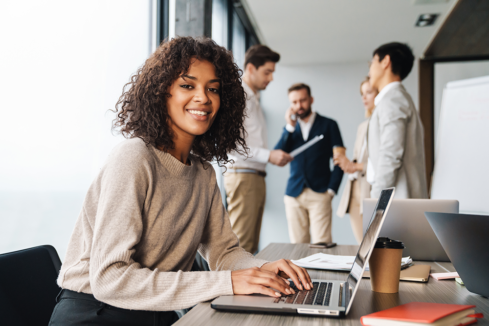 Face of a female professional smiling at work while on a laptop