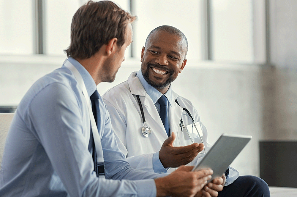 Male doctor smiling and speaking to a male professional