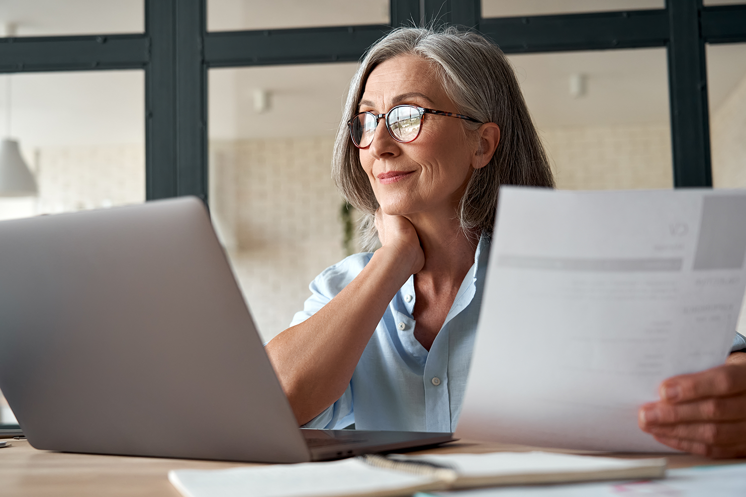 woman reviewing computer and paper