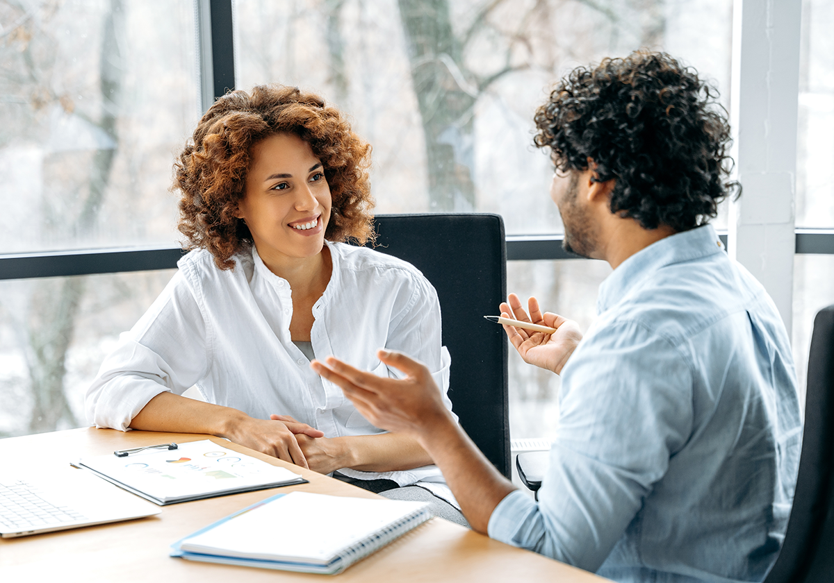 two colleagues talking at a desk