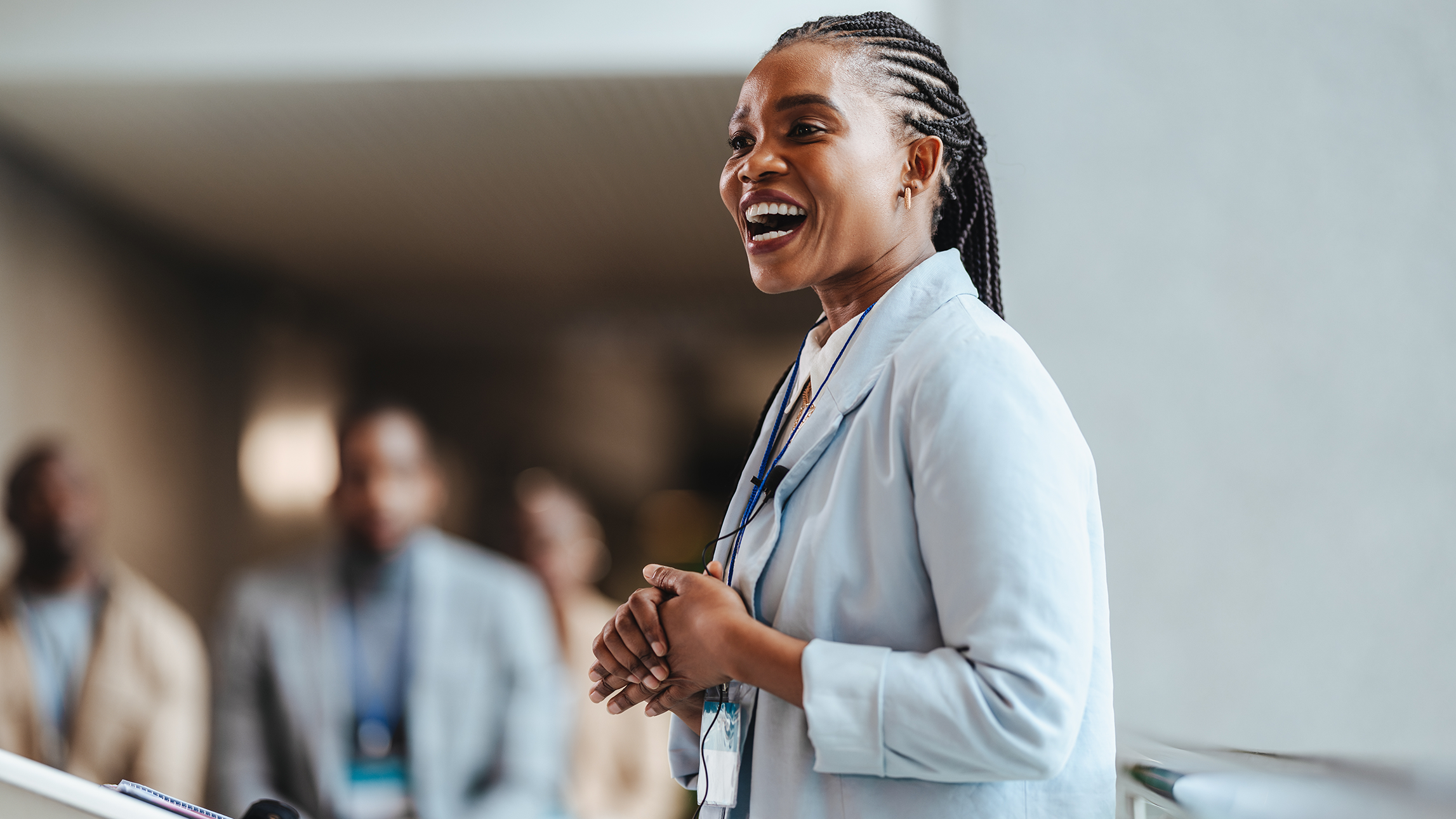 A female coach stands before an audience and lectures.