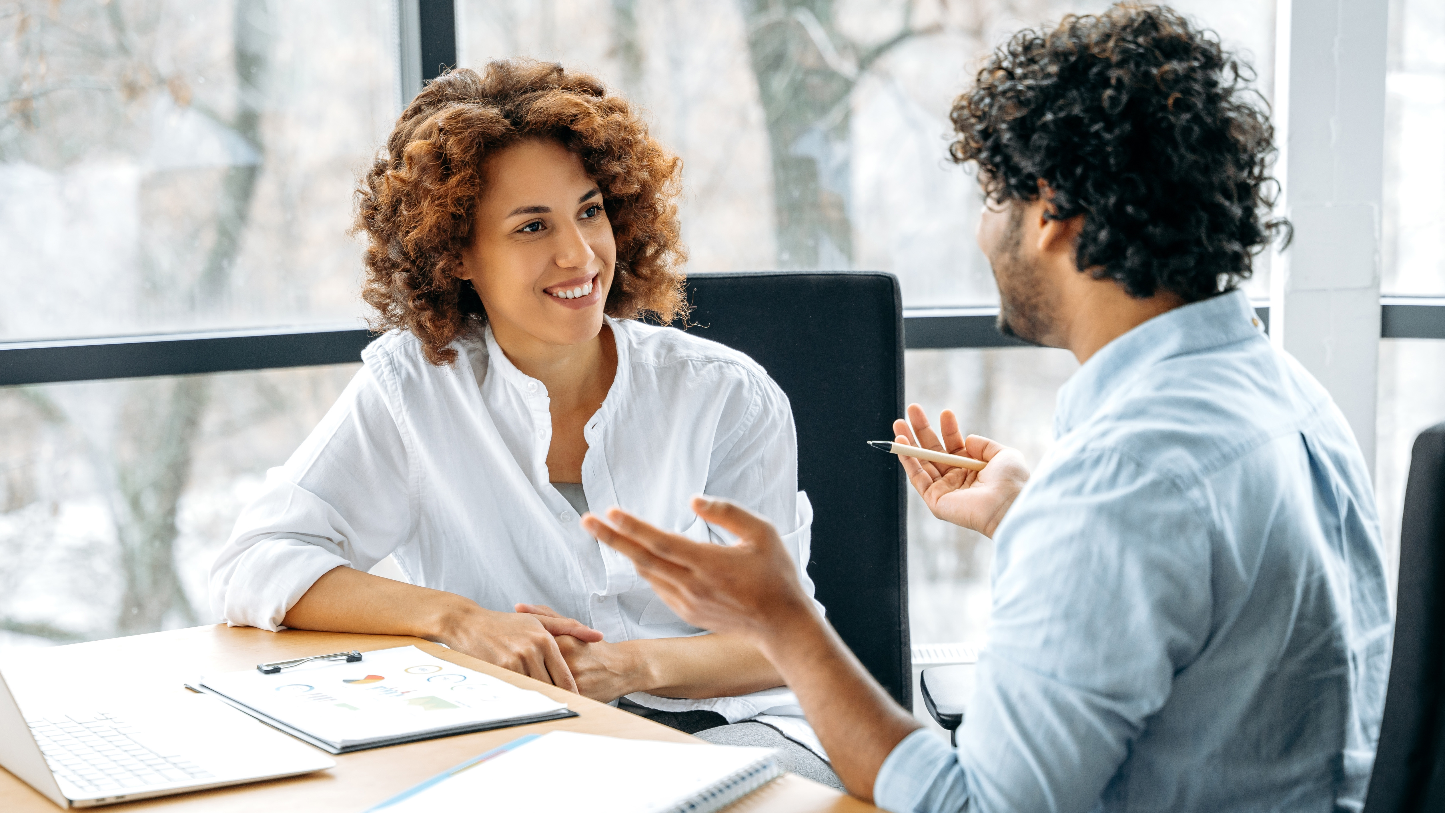A coach talks with an adult learner. The two sit at a table