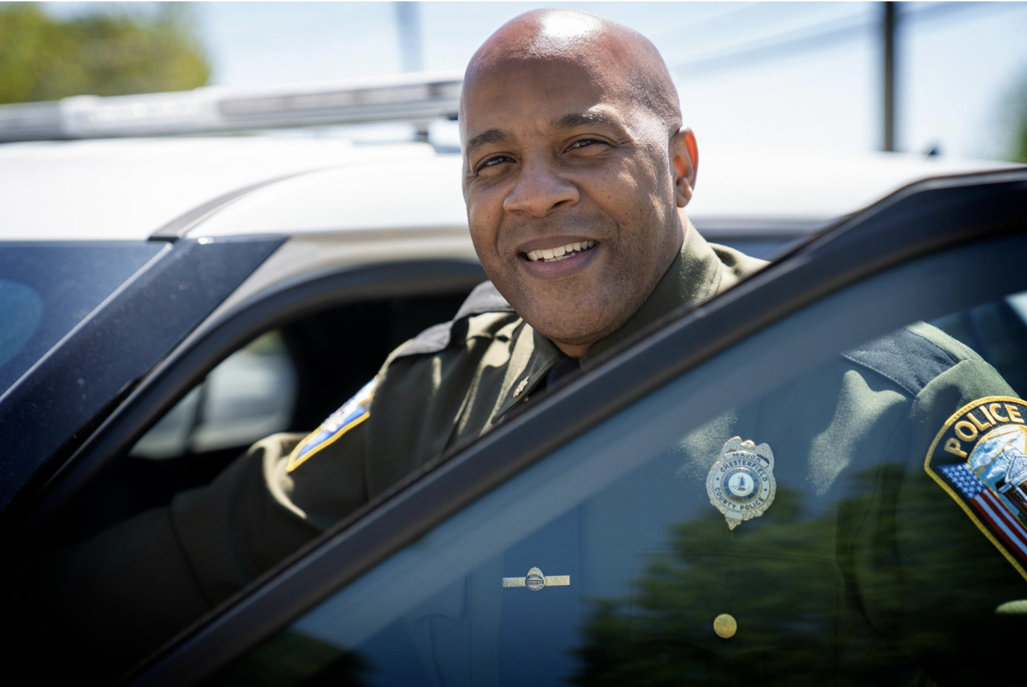 Major Frank Carpenter wears his police uniform and poses with his patrol vehicle